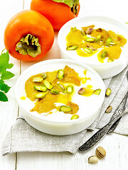 Image showing Dessert of yogurt and persimmon two bowls on light board