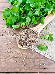 Image showing Coriander seeds in wooden spoon on old board top