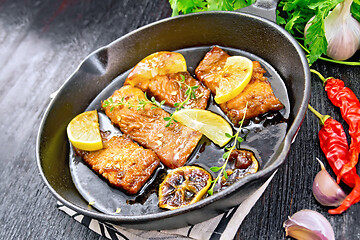 Image showing Salmon with sauce in pan on dark board