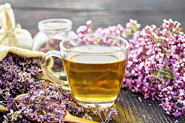 Image showing Tea of oregano in cup with spoon on dark board