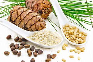 Image showing Flour cedar and nuts in two spoons on light board