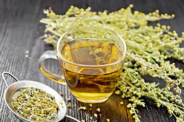 Image showing Tea of gray wormwood in glass cup with strainer on wooden board