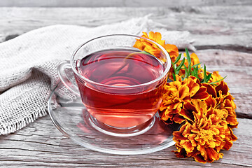 Image showing Tea herbal of marigolds in glass cup on old board