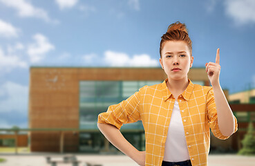 Image showing red haired teenage girl with finger up over school