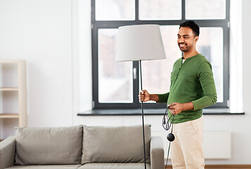 Image showing happy indian man holding floor lamp at home