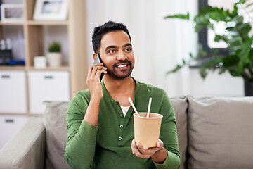 Image showing smiling indian man eating takeaway food at home