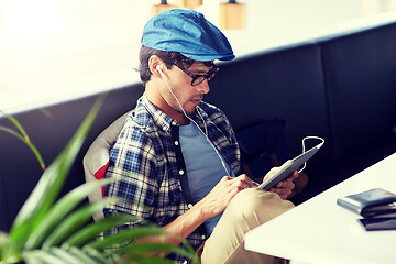 Image showing man with tablet pc and earphones sitting at cafe