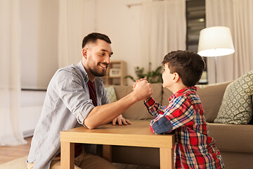 Image showing happy father and little son arm wrestling at home