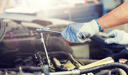 Image showing mechanic man with wrench repairing car at workshop