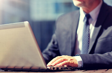 Image showing senior businessman with laptop at outdoor cafe