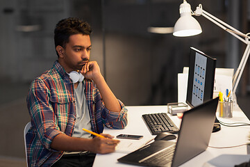 Image showing creative man with laptop working at night office