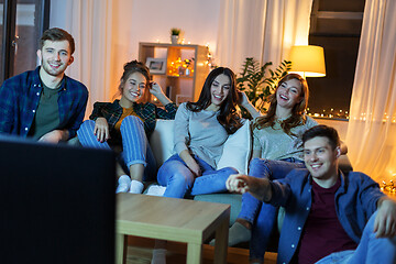 Image showing happy friends watching tv at home in evening