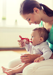 Image showing happy mother with spoon feeding baby at home