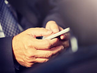 Image showing senior businessman texting on smartphone in car