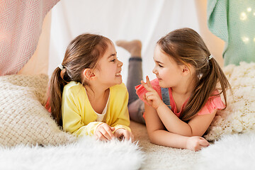 Image showing happy girls lying in kids tent and talking at home