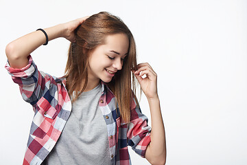 Image showing Smiling teen girl touching her hair looking down, studio portrait