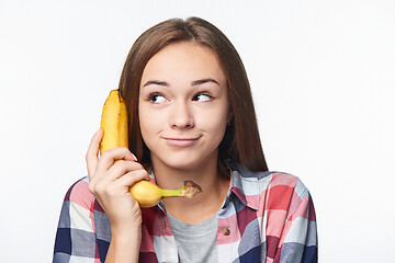 Image showing Teen girl holding banana like a phone, looking to side