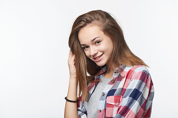 Image showing Smiling teen girl touching her hair looking at camera