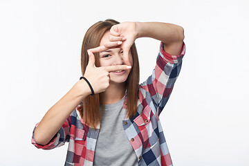 Image showing Smiling teen girl looking at camera through finger frame