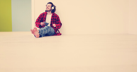 Image showing young man listenig music on tablet at home