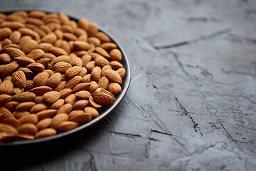 Image showing Whole almond nuts in black plate placed on black stone table