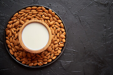 Image showing Composition of almonds seeds and milk, placed on black stone background.