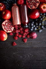 Image showing Various fresh red, purple black fruits. Mix of fruits and bottled juices on black