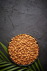 Image showing Composition of Whole almond nuts in black plate placed on black stone table