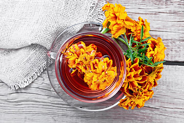 Image showing Tea herbal of marigolds in glass cup on board top