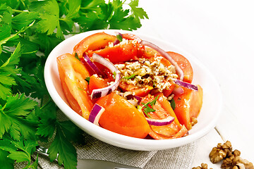 Image showing Salad with tomato and walnut in plate on light wooden board