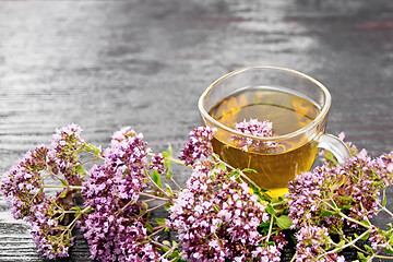 Image showing Tea of oregano in glass cup on dark board