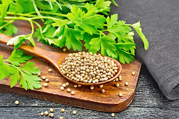 Image showing Coriander seeds in wooden spoon on black board