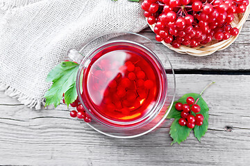 Image showing Tea from viburnum in cup with berries on old board top