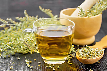 Image showing Tea of gray wormwood in glass cup with mortar on dark board