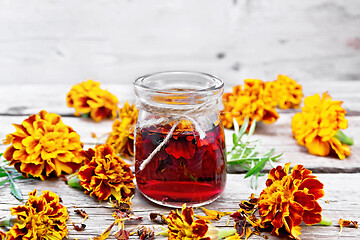 Image showing Alcohol tincture of marigolds in jar on old board