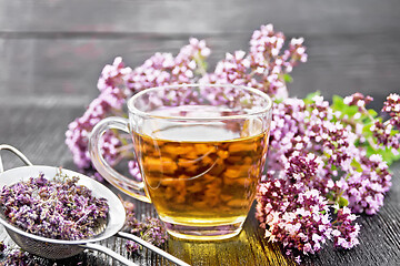 Image showing Tea of oregano in cup with strainer on board