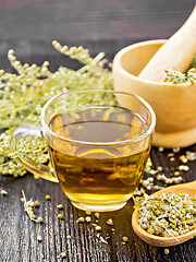 Image showing Tea of gray wormwood in glass cup with mortar on wooden board