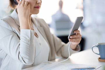 Image showing businesswoman with earphones and smartphone