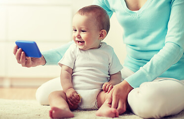 Image showing happy mother showing smartphone to baby at home