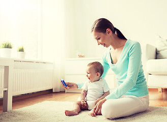 Image showing happy mother showing smartphone to baby at home