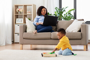 Image showing mother using laptop and baby playing toy blocks