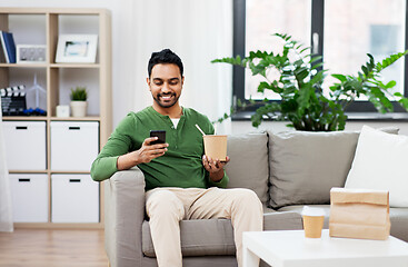 Image showing smiling indian man eating takeaway food at home