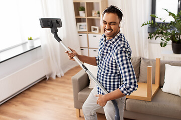 Image showing man in headphones with vacuum cleaner at home