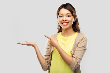 Image showing happy asian woman holding something on hand