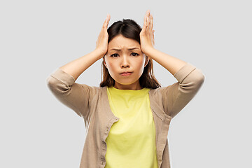 Image showing stressed asian woman holding to her head