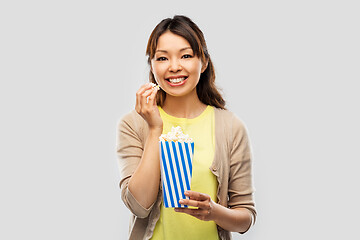 Image showing smiling asian woman eating popcorn