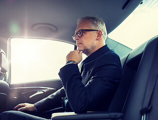 Image showing senior businessman driving on car back seat