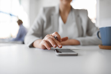 Image showing hand of businesswoman using smartphone at office