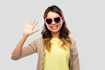 Image showing asian woman in heart-shaped sunglasses waving hand