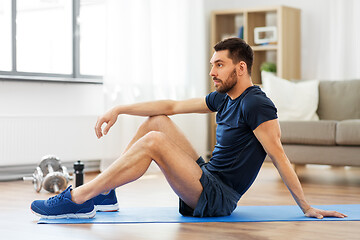 Image showing man resting on exercise mat at home